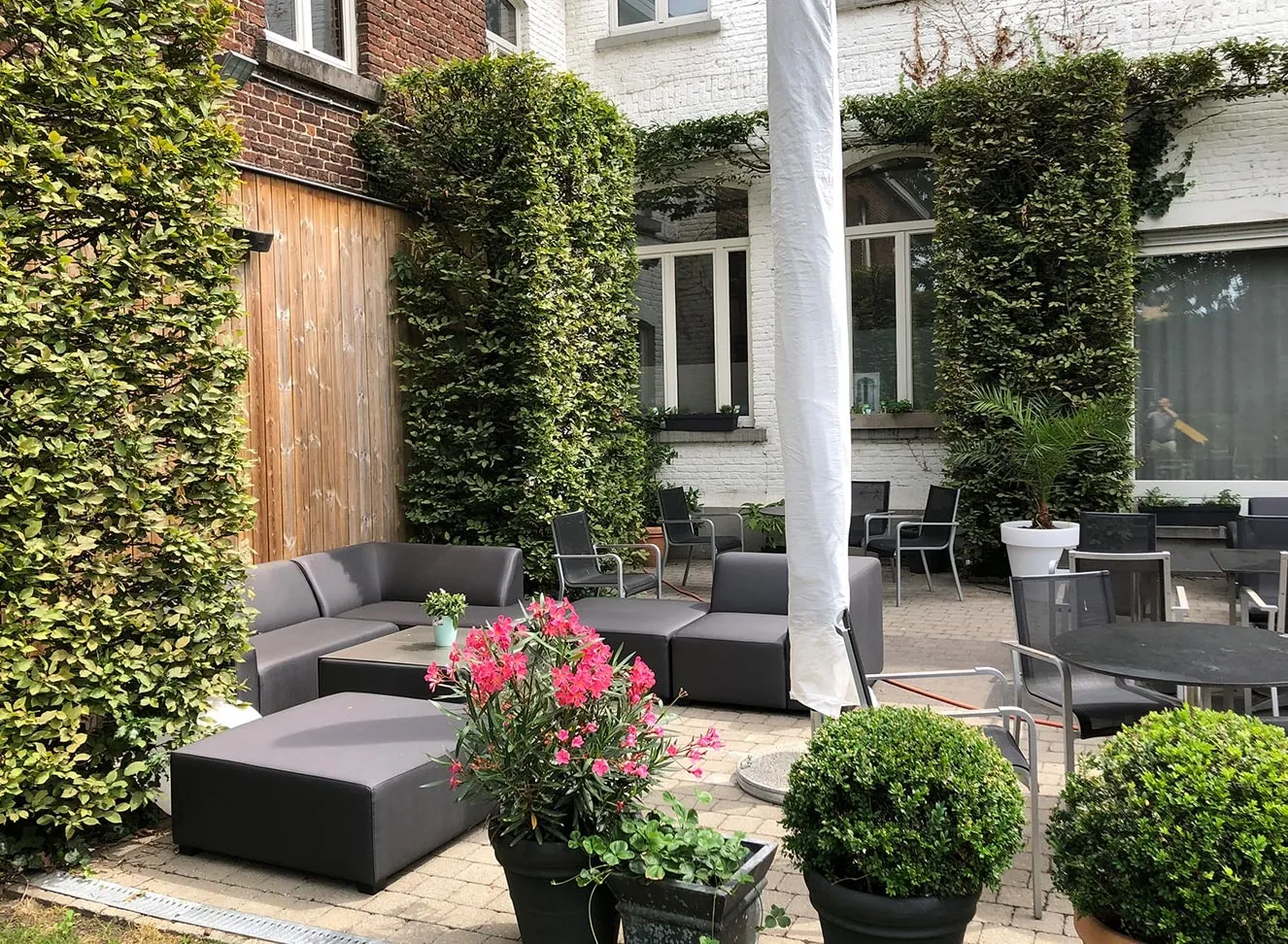 Loungezetels en bloembakken in de binnentuin, tussen begroeide muren